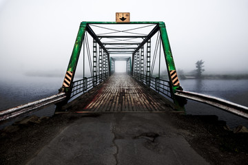 Old river bridge over a foggy river