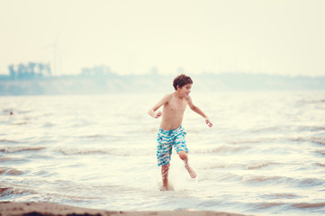 happy boy jumping in the waves at a beach in summer
