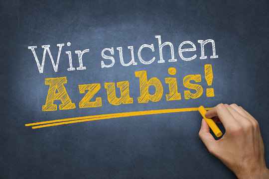 Hand schreibt mit Kreide Text "Wir suchen Azubis!" auf Tafel