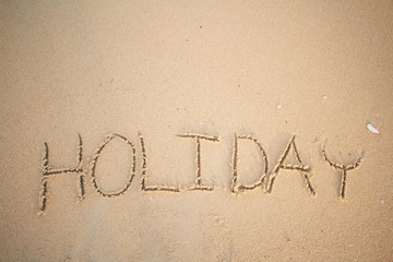 The word holiday written in sand on beach