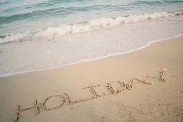 The word holiday written in sand on beach