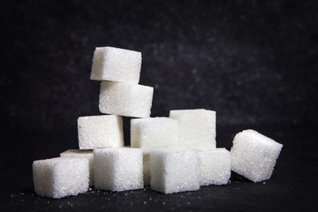 cloose up white sugar cubes on black stone plate background