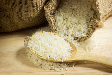 White uncooked rice in small burlap sack and in spoon