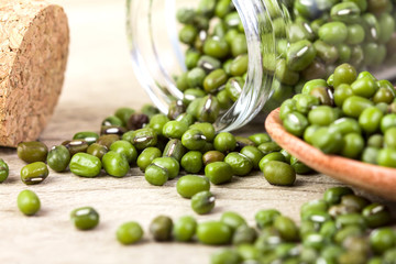 close up green mung beans in wooden spoon on wood plate