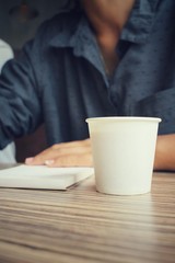 Woman with pen writing on paper and coffee cup