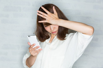 スマートフォン　/ 頭を抱える女性