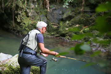 Fly-fisherman fishing in river on summer season