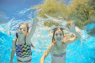 Obraz na płótnie Canvas Children swim in pool or sea underwater, happy active girls have fun in water