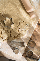 Cookie cutter on cake dough and rolling pin on a wooden board