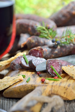 Südtiroler Brettljause mit deftigen Kaminwurzen und knusprigem Schüttelbrot, dazu ein Glas Südtiroler Rotwein
