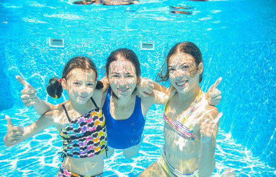 Family swim in pool underwater, happy active mother and children have fun in water