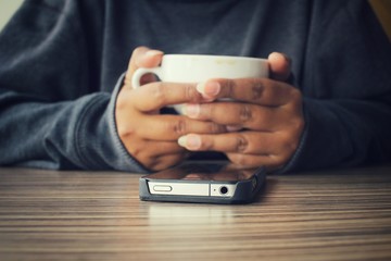 Woman using smart phone with coffee cup