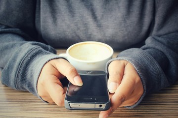 Woman using smart phone with coffee cup