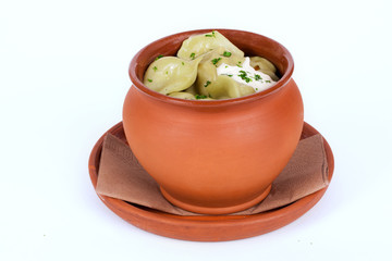 dumplings with greens and sour cream pot isolated white