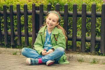  laughing schoolgirl  sitting on the street 