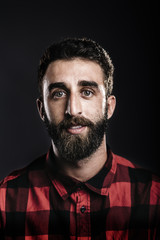 Portrait of a happy young man with beard smiling against gray ba