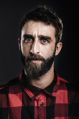 Portrait of a young man with beard angry against gray background