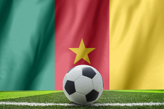 Soccer ball and national flag of Cameroon lies on the green gras