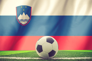 Soccer ball and national flag of Slovenia lies on the green gras