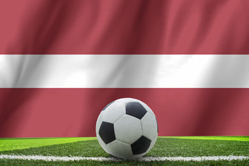 Fototapeta premium Soccer ball and national flag of Latvia lies on the green grass