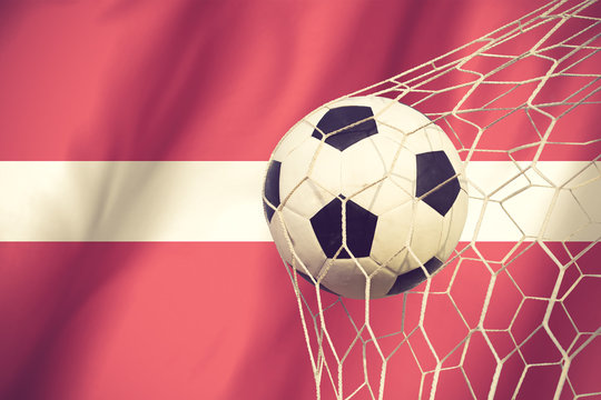 Latvia flag and soccer ball, football in goal net vintage color