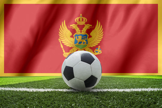 Soccer ball and national flag of Montenegro lies on the green gr