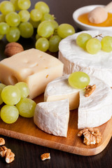 cheeses, grapes and walnuts on a wooden background
