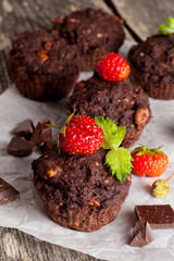 Chocolate cupcakes with strawberries on wooden background