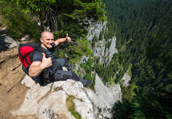 Hiker sitting on the edge of a very high cliff © Xalanx