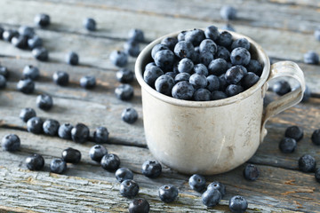 Blueberries in mug on a blue wooden background