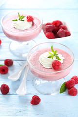 Sweet raspberry mousse in glass on blue wooden table