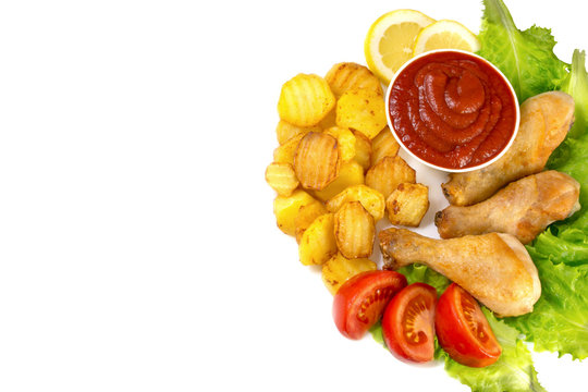 chicken legs on a white plate with slices of tomato and lettuce and french fries and ketchup top view isolated on white background

