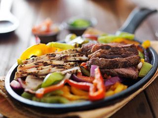 steak and chicken fajitas close up in cast iron fajita skillet