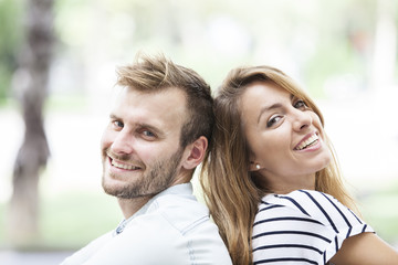 Obraz premium Young couple sitting back to back. Smiling and in love