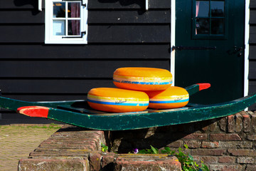 Dutch Cheese wheels on a green cart with farm house in the background