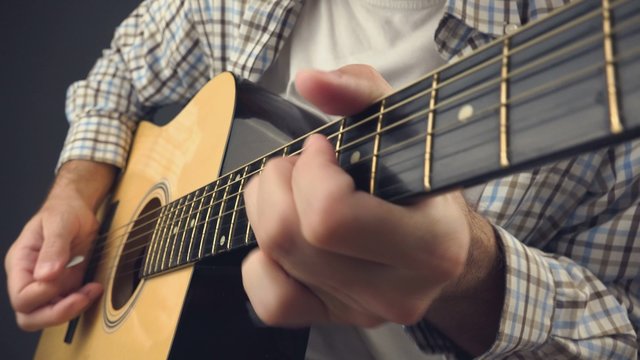 Musician playing rock tune on acoustic guitar, unplugged blues rock music performance indoors, close up, 4k uhd footage.