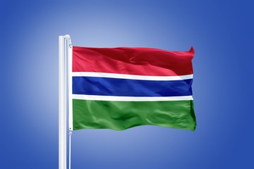 Fototapeta na wymiar Flag of Gambia flying against a blue sky