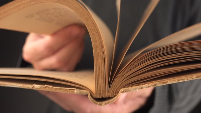 Man turning yellow pages of old vintage book in search for text and valuable information, 4k uhd footage