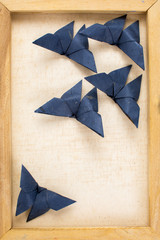 Vintage image of dark blue origami butterflies on the canvas fra