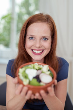 lächelnde frau hält eine schale salat in den händen