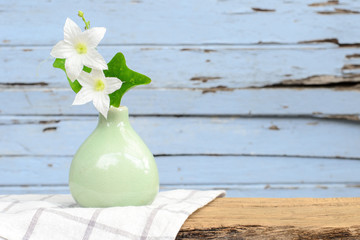 White flowers in the vase put on old wood.