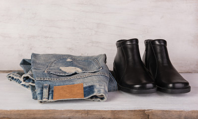Blue jeans and black shoes on grunge white wood background