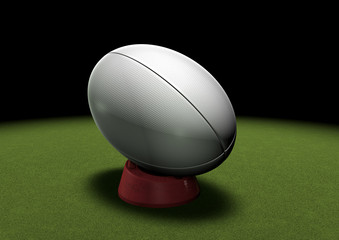 Rugby ball on kicking tee under spotlight