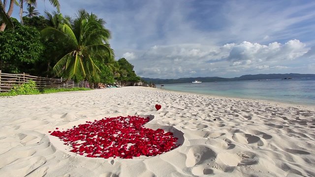 Heart of roses petals on tropical sandy beach. Nobody. Love concept
