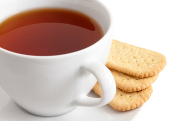 Detail of a white ceramic cup of rooibos tea with finger biscuit