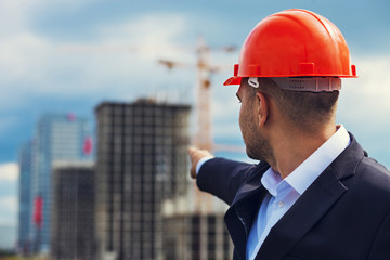 Worker engineer in helmet pointing at construction. Labor day