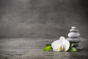 Foto op Plexiglas White orchid and spa stones on the grey background. © gitusik
