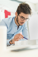 young engineer at work on a model house in his office