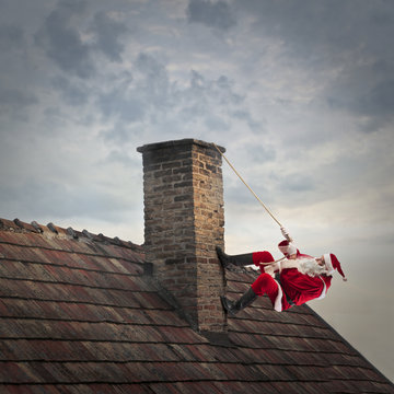 Santa Claus climbing a roof