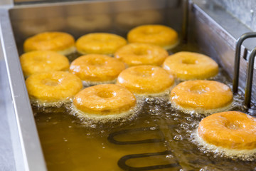 fried equal round doughnuts in deep-fryer